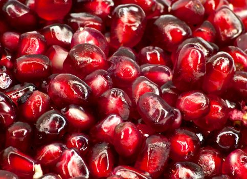 Extreme close up background of a red juicy ripe pomegranate fruit seeds 