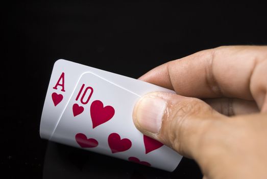 Blackjack cards held by hand against black background