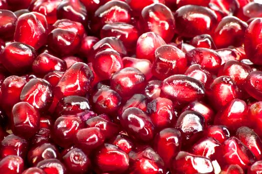 Extreme close up background of a red juicy ripe pomegranate fruit seeds 