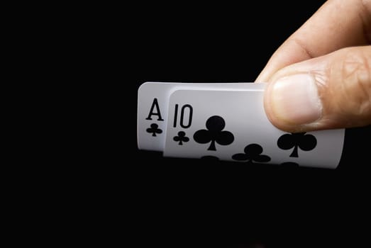 Blackjack cards held by hand against black background