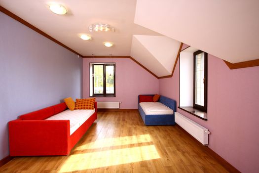 Blue and red sofas in a bedroom with pink walls and windows
