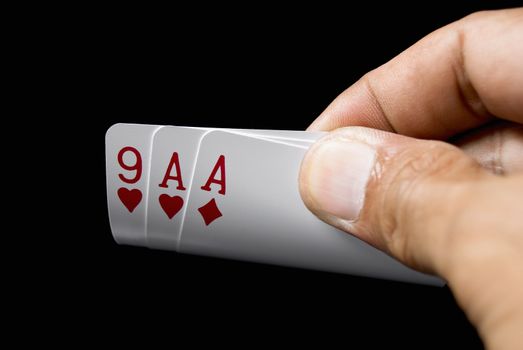 Blackjack cards held by hand against black background