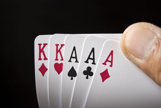 Three Aces and Two Kings held by hand against black background