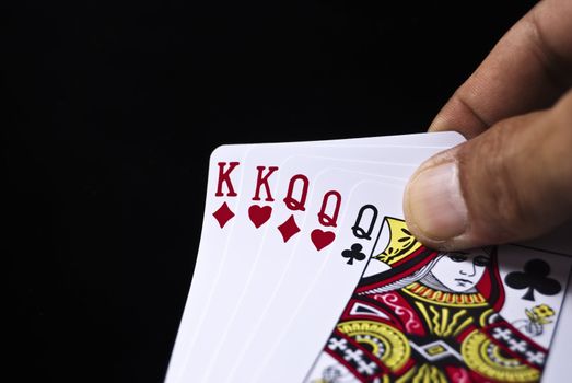 Three Kings and three Queens held by hand against black background