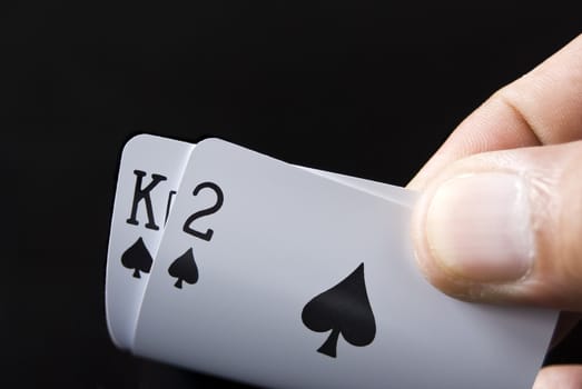 Blackjack cards held by hand against black background