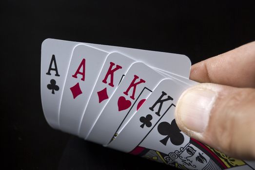 Two Aces and three Kings held by hand against black background