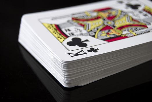 Deck of cards against black background; King of Clubs right side up
