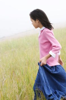 Girl running down grassy hill holding skirt