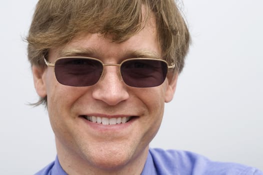 Man with sunglasses smiling outdoors on misty, cloudy day