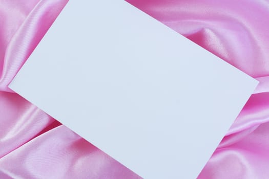 Blank white card on pink satin cloth