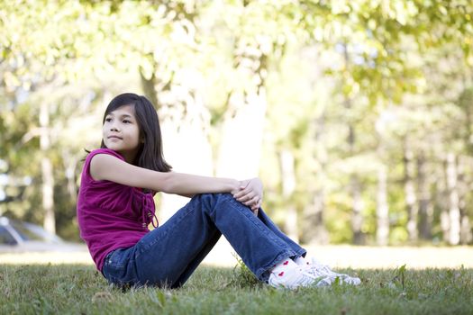 Little girl sitting on grass looking over shoulder