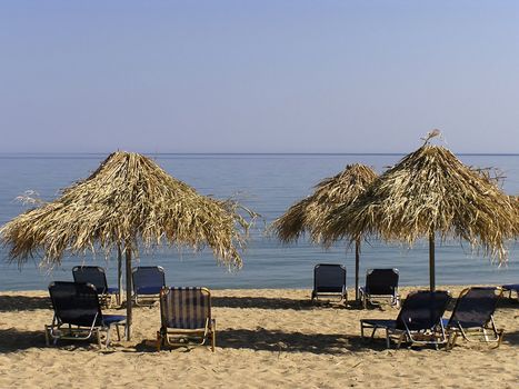 Sunshades and sunbeds at sandy greek beach.