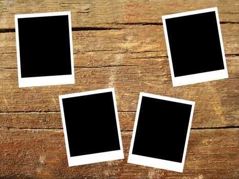 set of four old blank polaroids frames lying on a wood surface 
    