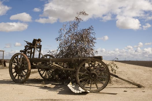 Old agricultural wagon on a farm in California with cumulus clouds in background
