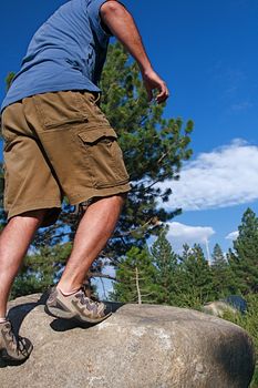 Trail runner climbing a steep rock in his path