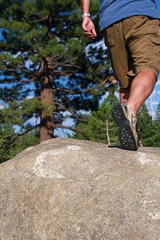 Trail runner climbing a steep rock in his path