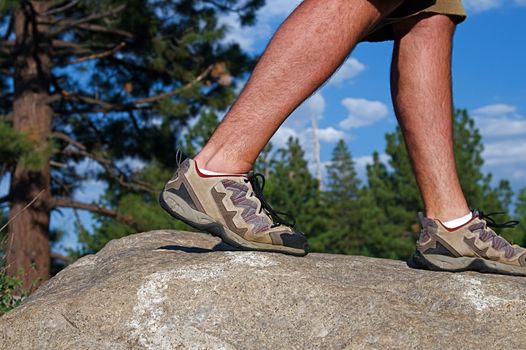 Trail runner climbing a steep rock in his path