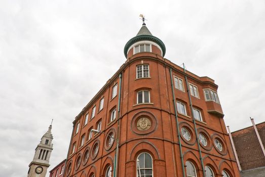 Corner View of a Red Brick Nineteenth Century Office Building with Tower and Weathervane