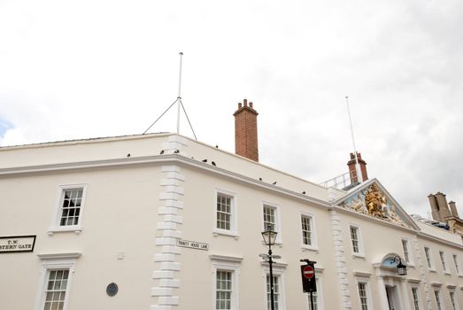 An old white building with the English Royal Family Coat of Arms as detail