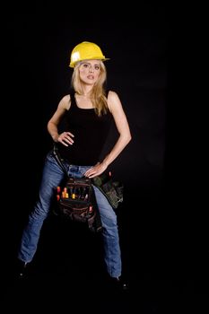 sexy blond female construction worker with hard hat and tool pouch on black background