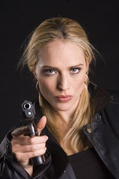 Sexy blond woman with gun in leather jacket on a black background