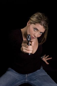 Sexy blond in sweater and jeans with semi-automatic handgun up to head