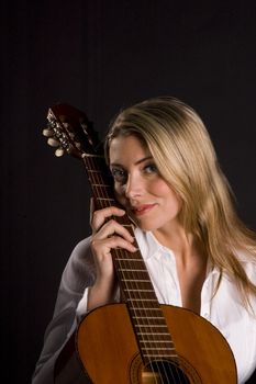 Guitarist leaning against intrument with smile on a black background