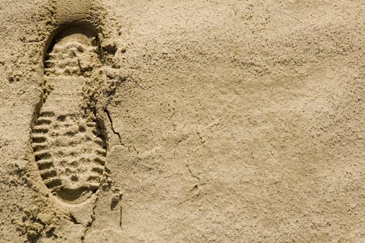 single footprint impression in the desert sand on left of image