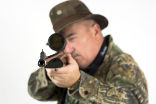 Man in camouflage clothing with rifle taking aim at target