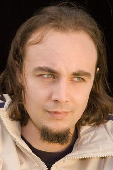 young man with green eyes and beard over black