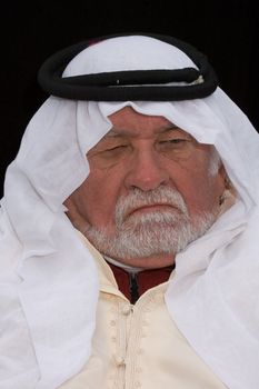 older middle-eastern man with white beard, in Arabian headress and sunglasses isolated on black