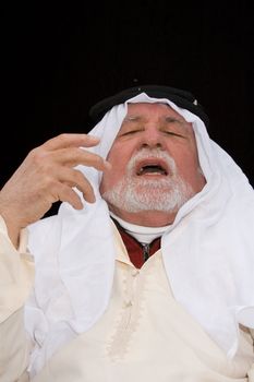 older middle-eastern man with white beard, in Arabian headress and sunglasses isolated on black