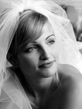 Black and white portrait of young adult bride wearing wedding dress veil.