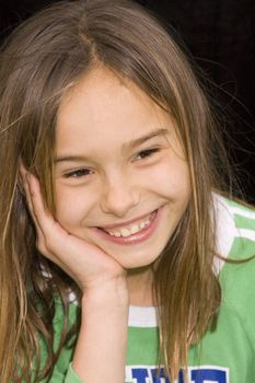 Cute brunette girl smiling and resting head in hand on black