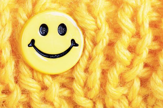 Macro view of yellow knitting with yellow smile button