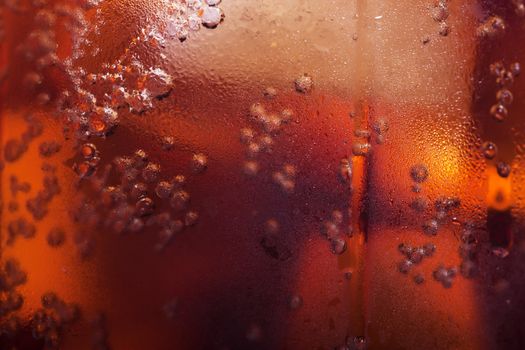 Macro view of cold cola in a glass with ice cubes