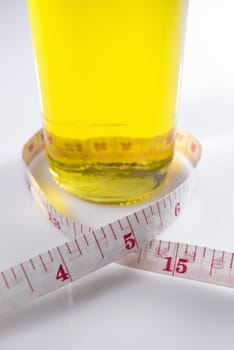 Studio shot of olive oil and measuring tape against white background