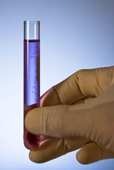 Lab personnel handles test tube, studio shot
