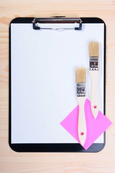 Two brushes and office scratch paper against Blank Clipboard.