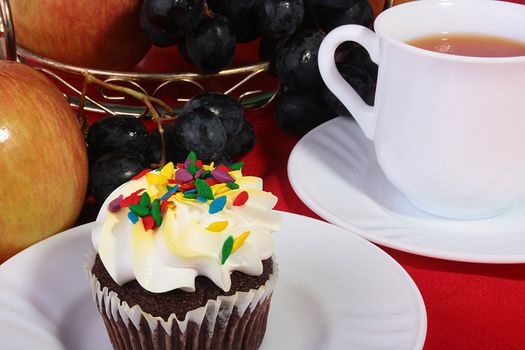 Cake with a cream, fruit and tea by a breakfast or a lunch.