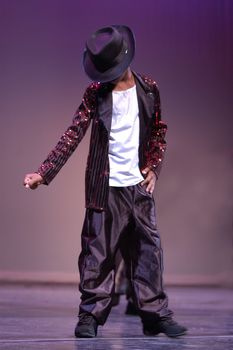 A boy dances on the stage imitating Micheal Jackson.