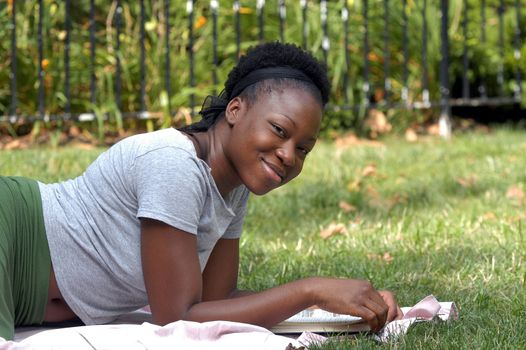 Young  afican american lady looks up from a book and smiles.