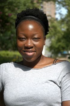 A young african american woman sits and smiles.