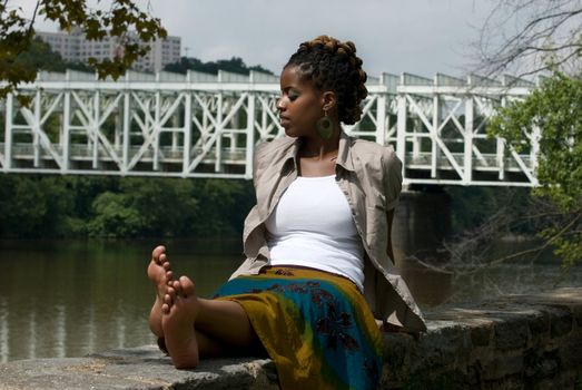 African American woman sits and relaxes by the river front