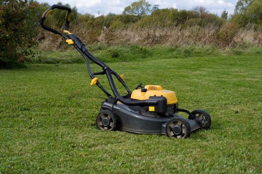 Yellow lawn mower on the green field.