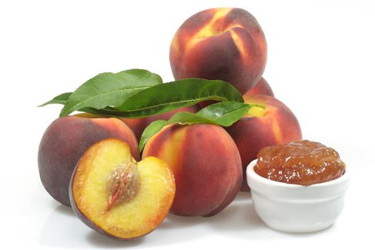 Peach jam in a bowl with fresh peaches over white background