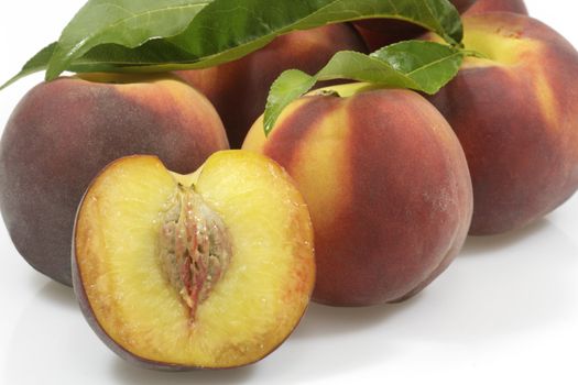 Fresh peaches with leaves over white background