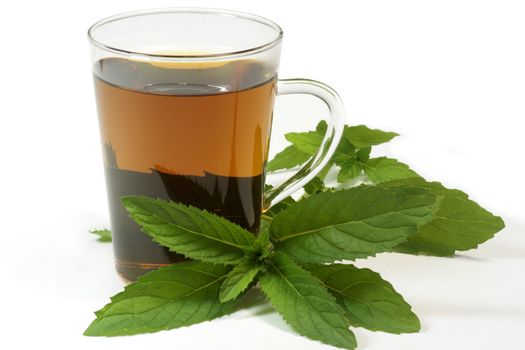 Herbal tea in a teaglass with peppermint leaves on white background