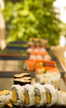 A series of sushi plates at an outdoor venue with a shallow depth of field