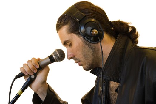 Profile of a young man in a leather jacket singing in a romantic way in a microphone.